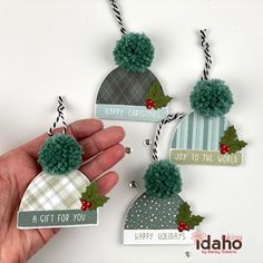 hand holding three christmas ornaments with pom - poms hanging from the top and bottom