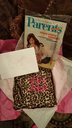 a leopard print purse and magazine on a pink tissue paper with a note attached to it