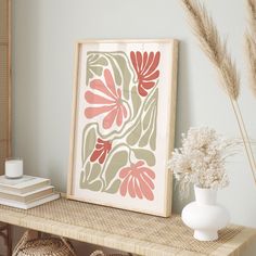 a painting on a shelf next to a vase with flowers in it and some books