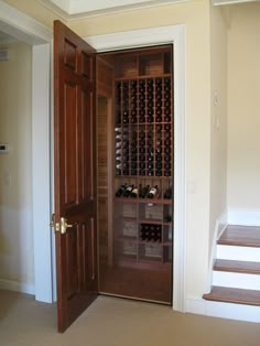 a wine cellar in the corner of a room with an open door to another room