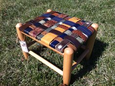 a small wooden stool made out of patchwork fabric on the grass with a tag in front of it