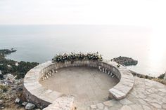 an outdoor seating area overlooking the ocean with flowers and candles on it's wall