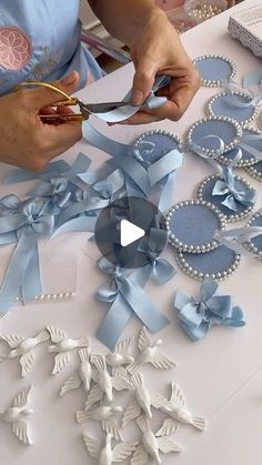 a woman cutting ribbon with scissors at a table covered in blue and white decorations on it