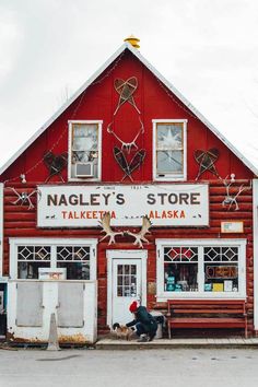 a red building with white trim and windows on the outside, has a sign that says nagley's store