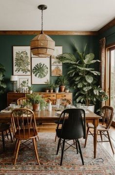 a dining room with green walls and plants on the wall, wooden table surrounded by chairs