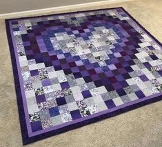 a purple and black quilt is laying on the floor