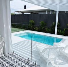 an outdoor pool surrounded by white chairs and a black and white checkered tile floor