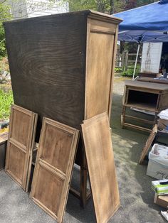 an assortment of wooden furniture on display at a flea market with tents in the background