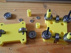 four pieces of yellow plastic and metal on top of a wooden table with screws