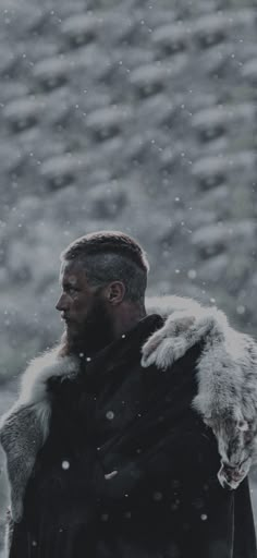 a man standing in the snow wearing a black coat