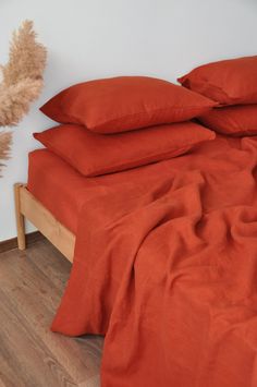 a bed with orange sheets and pillows on top of it next to a teddy bear