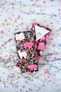 a pink and black bag with sprinkles on it next to a pair of scissors