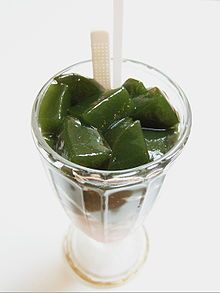 a glass filled with pickles on top of a white table