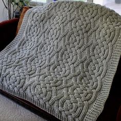 a couch with a blanket on top of it in front of a window and a potted plant