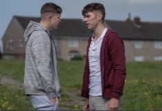 two young men standing next to each other in front of a field with yellow flowers