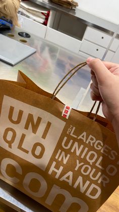 a person holding up a brown paper bag with the words uni ollo in your hand on it