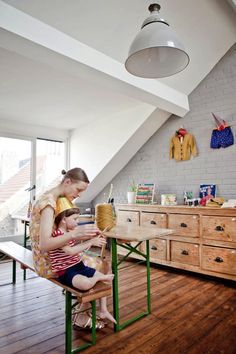 a woman sitting at a table with a child on her lap looking at an object