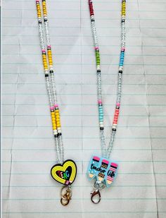 two necklaces with charms attached to them sitting on top of a piece of lined paper