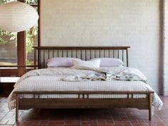 a bed sitting in the middle of a room next to a brick floor and windows