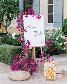 a sign that is sitting in the grass near some flowers and lemons next to it