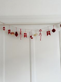 red and white christmas decorations hanging from a line on the wall in front of a door