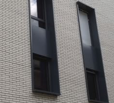 two windows on the side of a brick building