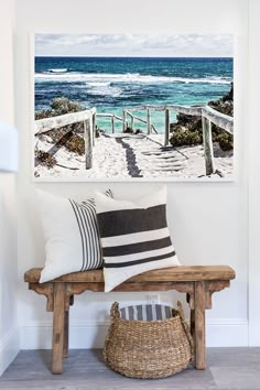 a wooden bench sitting next to a wall with paintings on it's sides and stairs leading to the beach