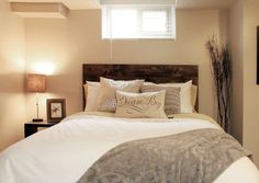 a bed with pillows and blankets on top of it next to a window in a bedroom