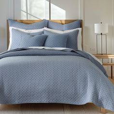 a bed with blue bedspread and pillows in a room