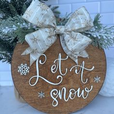 a wooden sign that says let it snow on the side of a tree with snowflakes