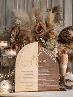 a wooden menu sitting on top of a table next to some candles and vases