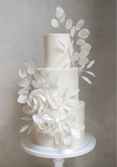 a three tiered white wedding cake with flowers on top