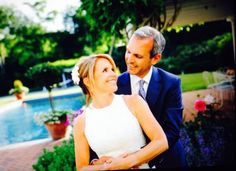 a man and woman standing next to each other in front of a pool