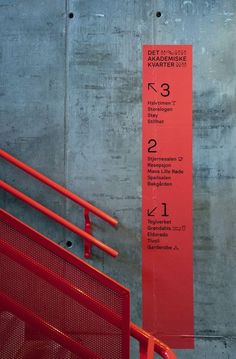 a red sign on the side of a building next to a metal fence and stairs