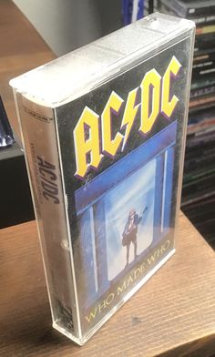 an ac / dc cd case sitting on top of a wooden table next to a computer keyboard