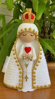 a crocheted figurine with a heart on it's chest, wearing a crown and holding a cross