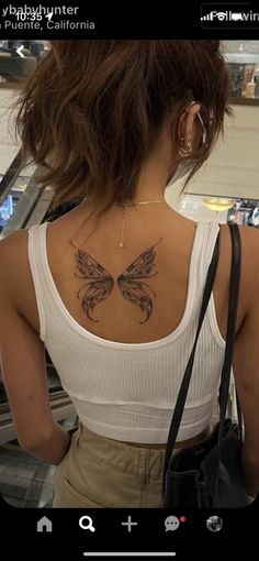 a woman with a butterfly tattoo on her back and shoulder, looking at an escalator