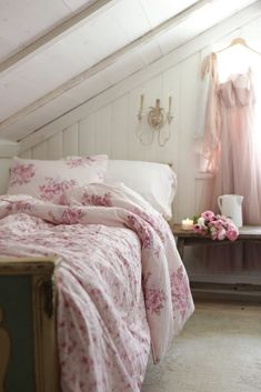 a bed with pink flowers on it in a bedroom next to a dresser and window