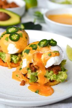 two burritos on a white plate with avocado and sour cream sauce