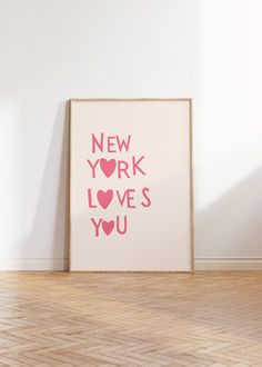 a framed print with the words new york loves you in pink on a white wall