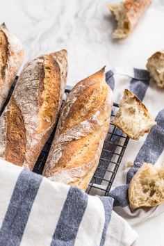 several loaves of bread sitting on top of a cooling rack next to a blue and white towel