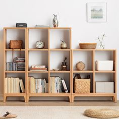 a bookshelf filled with lots of books next to a wall mounted clock and wicker basket