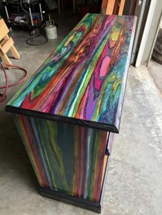 a multicolored wooden bench sitting on top of a cement floor