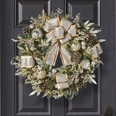 a wreath on the front door decorated with gold and silver bows, pine cones, evergreens and bells