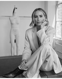 a black and white photo of a woman sitting in front of a mannequin