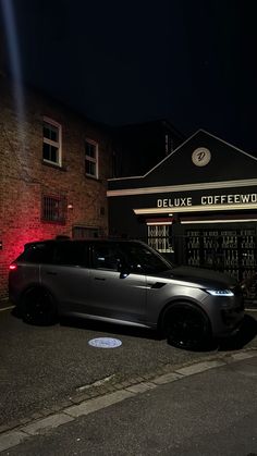 a grey car parked in front of a building at night with red lights on it