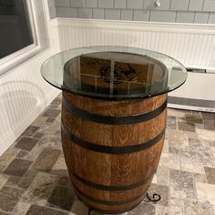 a wine barrel table with glass top in the middle of a tiled floored room