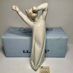 a figurine of a woman holding her arms up in front of a box