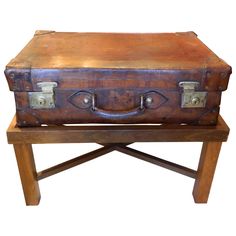 an old suitcase sitting on top of a wooden bench with metal handles and latches