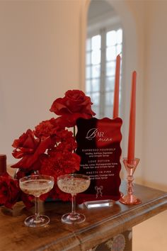 two wine glasses sitting on top of a wooden table next to flowers and an award plaque